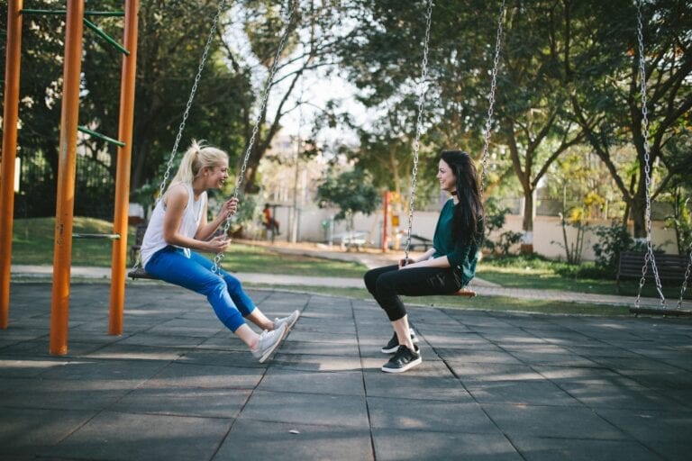 Photo of two teens talking on swings